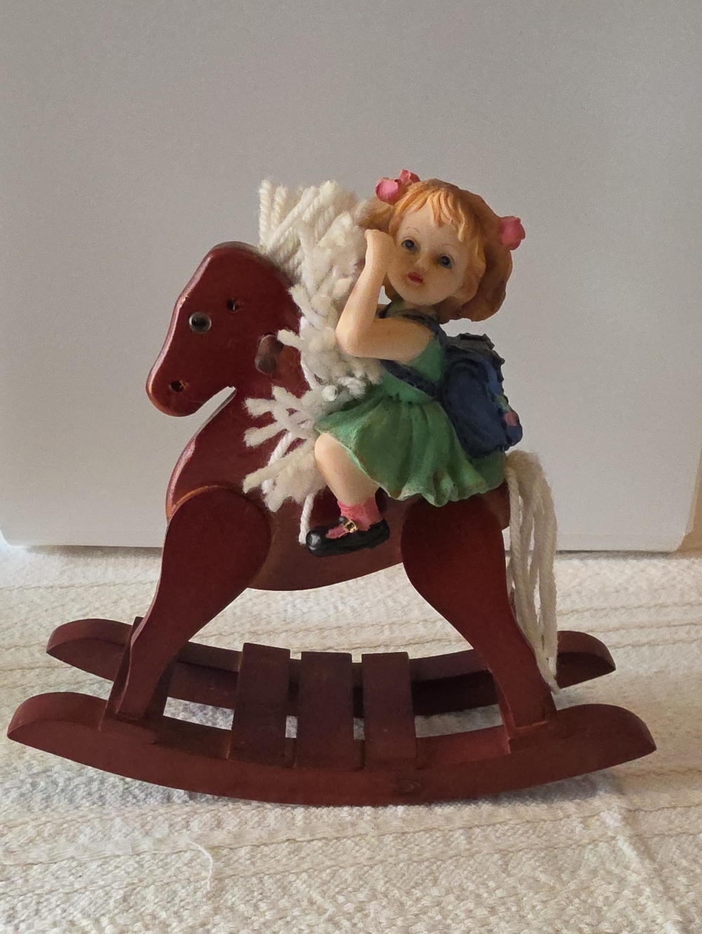 Collectible vintage porcelain doll figurine riding a small wooden rocking Horse